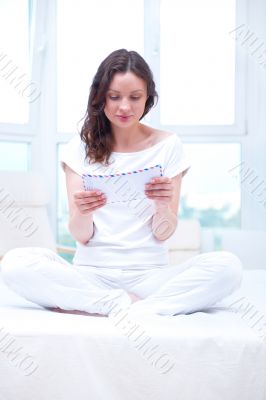 American or european young pretty woman sitting on bed in bright