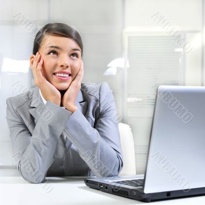 Young business woman on a laptop at her office. Daydreaming