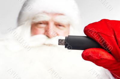 Traditional Santa Claus holding 3g usb modem in his arm on foreg