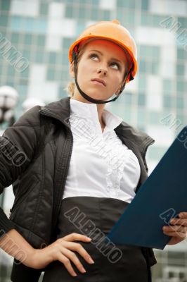 Young architect-woman wearing a protective helmet standing"