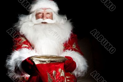 Santa sitting at the Christmas room and looking into the sack