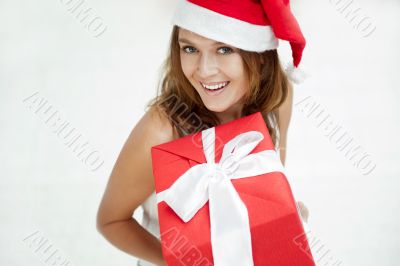Young happy girl in Christmas hat. Standing indoors and holding 