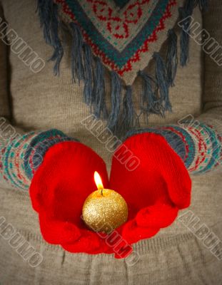 Human hands hold burning  golden candle