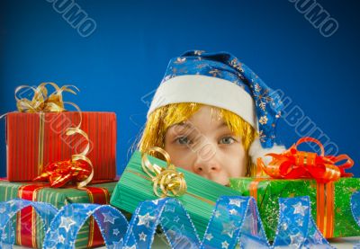 Surprised teen girl looking from behind the Christmas presents