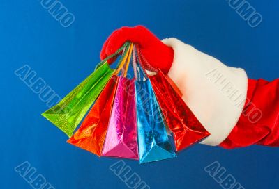 Santa`s hand holding colorful bags