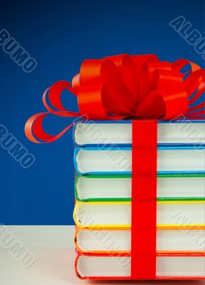 Stack of colorful books tied up with red ribbon