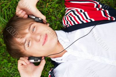 Student outside laying on grass and listening