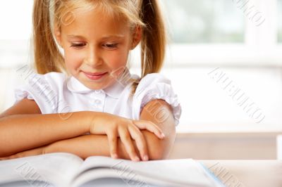 Image of smart child reading interesting book in classroom