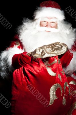 Santa sitting at the Christmas room and looking into the sack