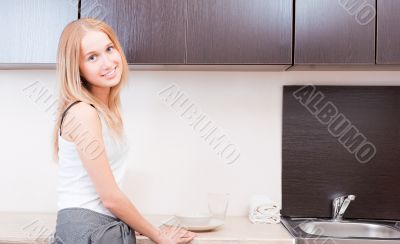 Portrait of beautiful relaxed young woman standing at the kitche