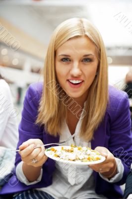 Closeup portrait of an attractive young woman eating fruit salad