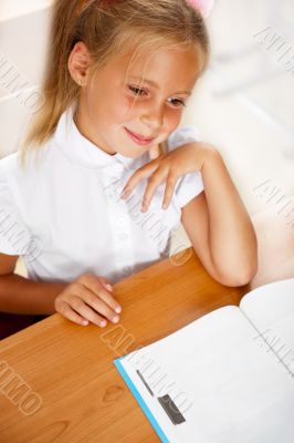 Image of smart child reading interesting book in classroom