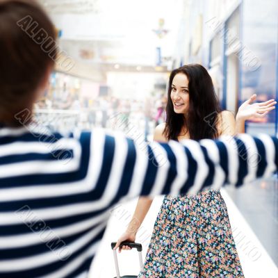 Young man meeting his girlfriend with opened arms at airport arr