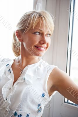 Closeup portrait of smiling woman standing near big window