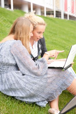 Portrait of two smiling women using laptop on