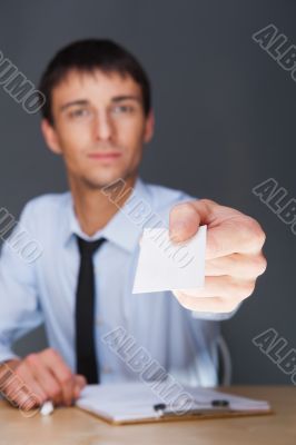 Business man handing a blank business card over grey background