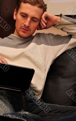 Happy young man  sitting on sofa at home</spa
