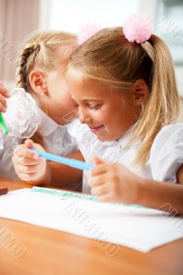 Two little girls gossip in classroom