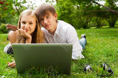 College students using laptop on campus lawn