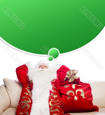 Traditional Santa Claus resting on sofa indoors and daydreaming.