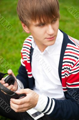 Student outside sitting on green grass and listening music via h