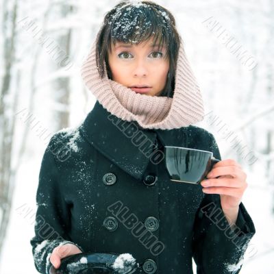 Portrait of young beautiful woman standing alone in winter park 