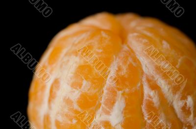 Close up photograph of a peeled Clementine orange on a black bac