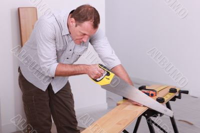 Man sawing a wooden floor