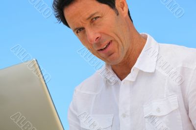 Man on laptop in blue sky
