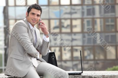 Businessman talking on phone in front of a laptop computer