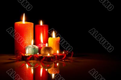 A lot of burning colorful candles against black background