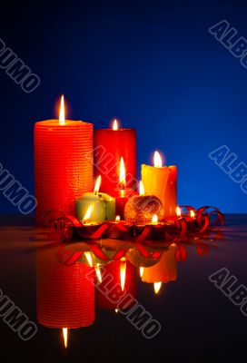 A lot of burning colorful candles against black background