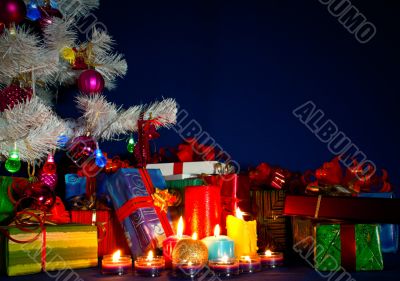 Christmas presents and burning candles against blue background