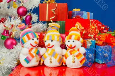 Three snowmen in front of the Christmas presents over the blue b