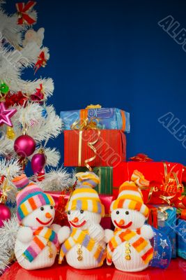 Three snowmen in front of the Christmas presents over the blue b