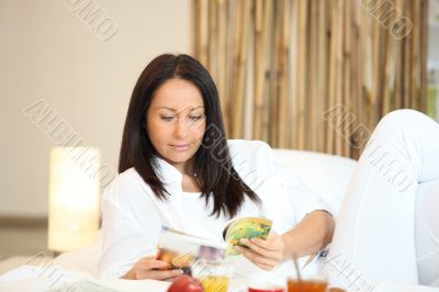 Woman reading a magazine over breakfast