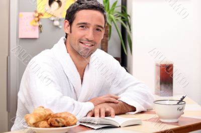 Man reading a book and eating a continental breakfast