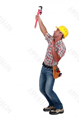 Tradesman using a pipe wrench to tighten an object