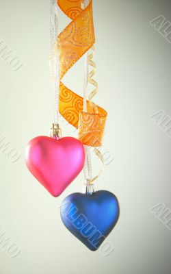 Two heart shaped toys hanging against light background