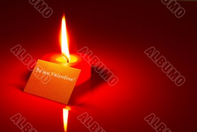Burning heart shaped candle and a Valentine`s card