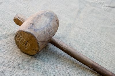 Old wooden mallet hammer on burlap background