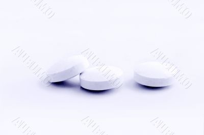 handful of white pills on a lid 