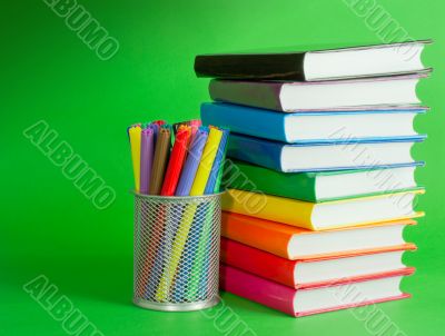 Stack of colorful books and socket with felt pens