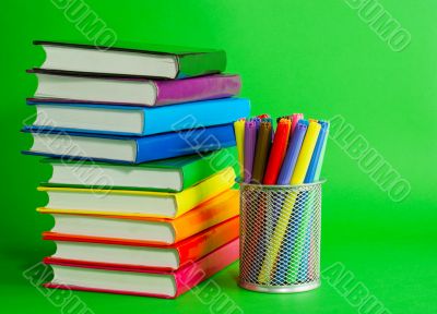 Stacks of colorful books and socket with felt pens