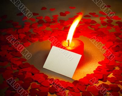 Burning heart shaped candle and a card