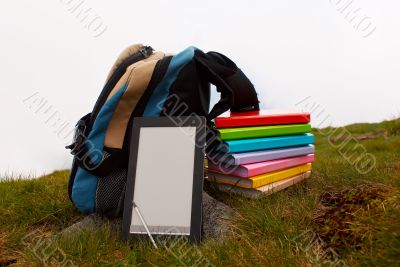 Stack of colorful books and electronic book reader