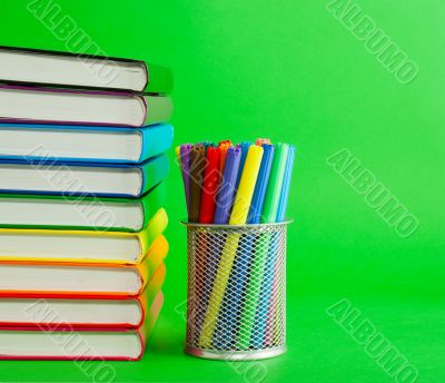 Stack of colorful books and socket with felt pens