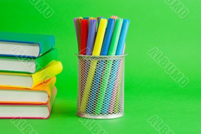 Stacks of colorful books and socket with felt pens