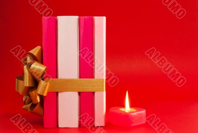 Row of books tied up with ribbon and burning candle