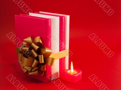 Row of books tied up with ribbon and burning candle